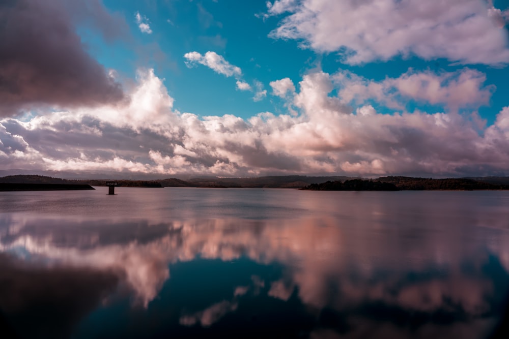 specchio d'acqua sotto cielo blu e nuvole bianche durante il giorno