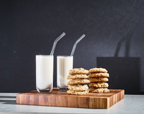 clear drinking glass with white liquid inside beside brown cookies