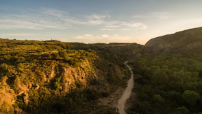 A winding hiking trail through lush green hills bathed in warm sunlight.