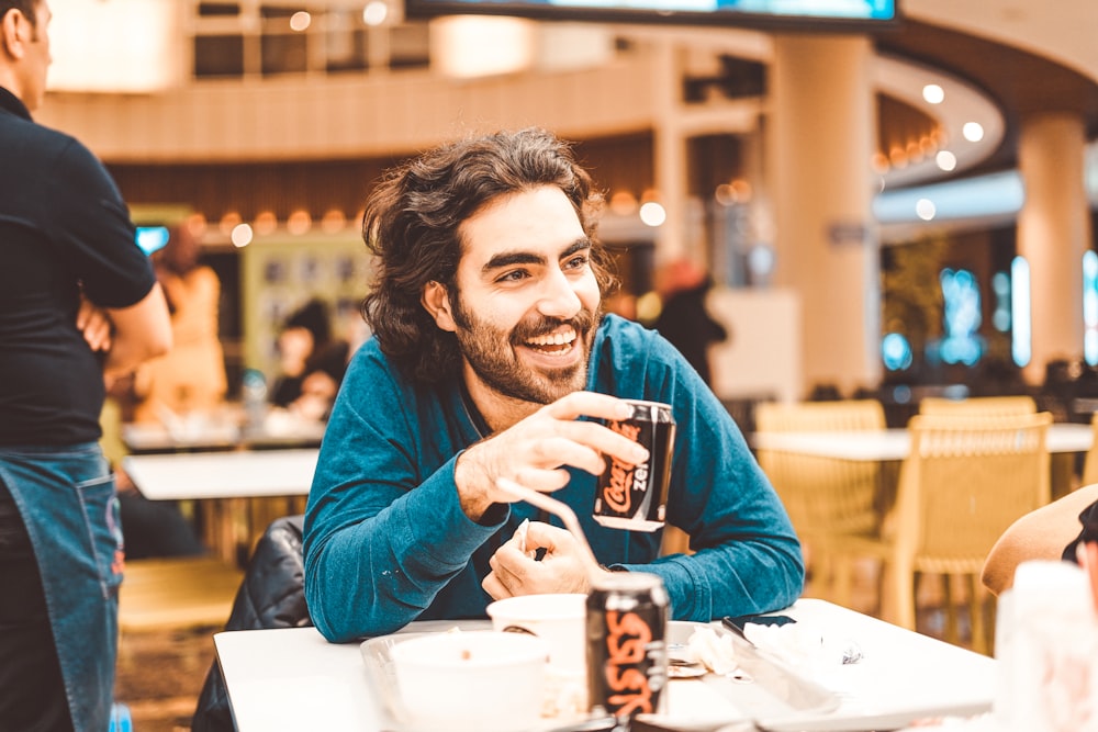 man in blue long sleeve shirt holding black and white ceramic mug