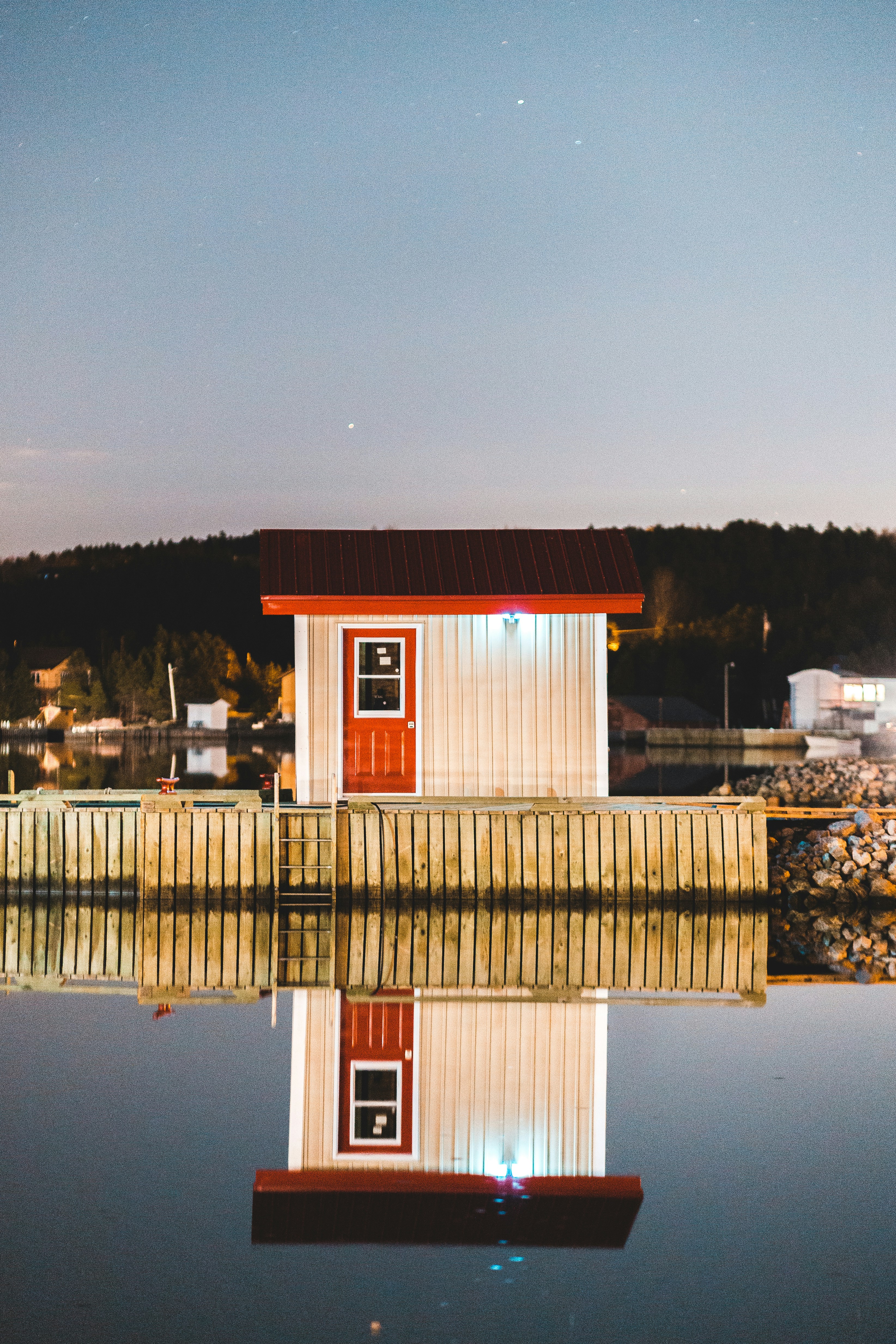 Red and white wooden house near body of water during night time photo ...