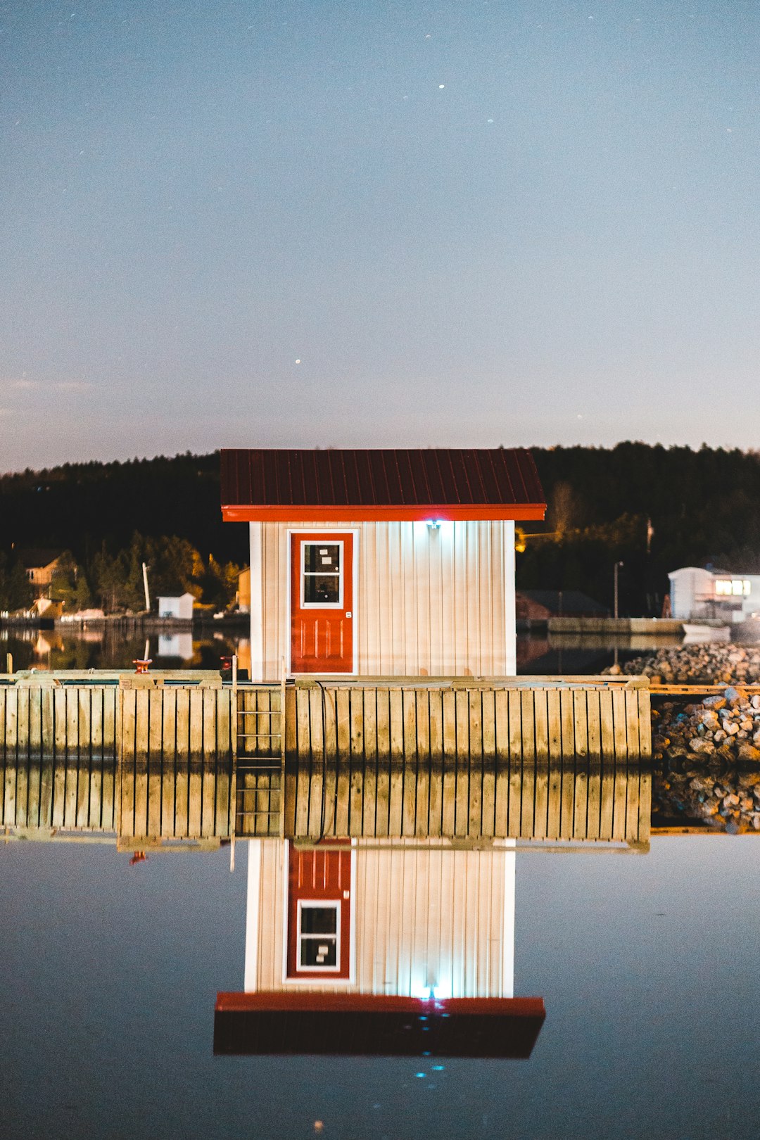 red and white wooden house near body of water during night time