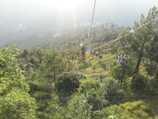 Tourists enjoying the ropeway ride over lush green hills near Banka, capturing the thrill and scenic beauty.
