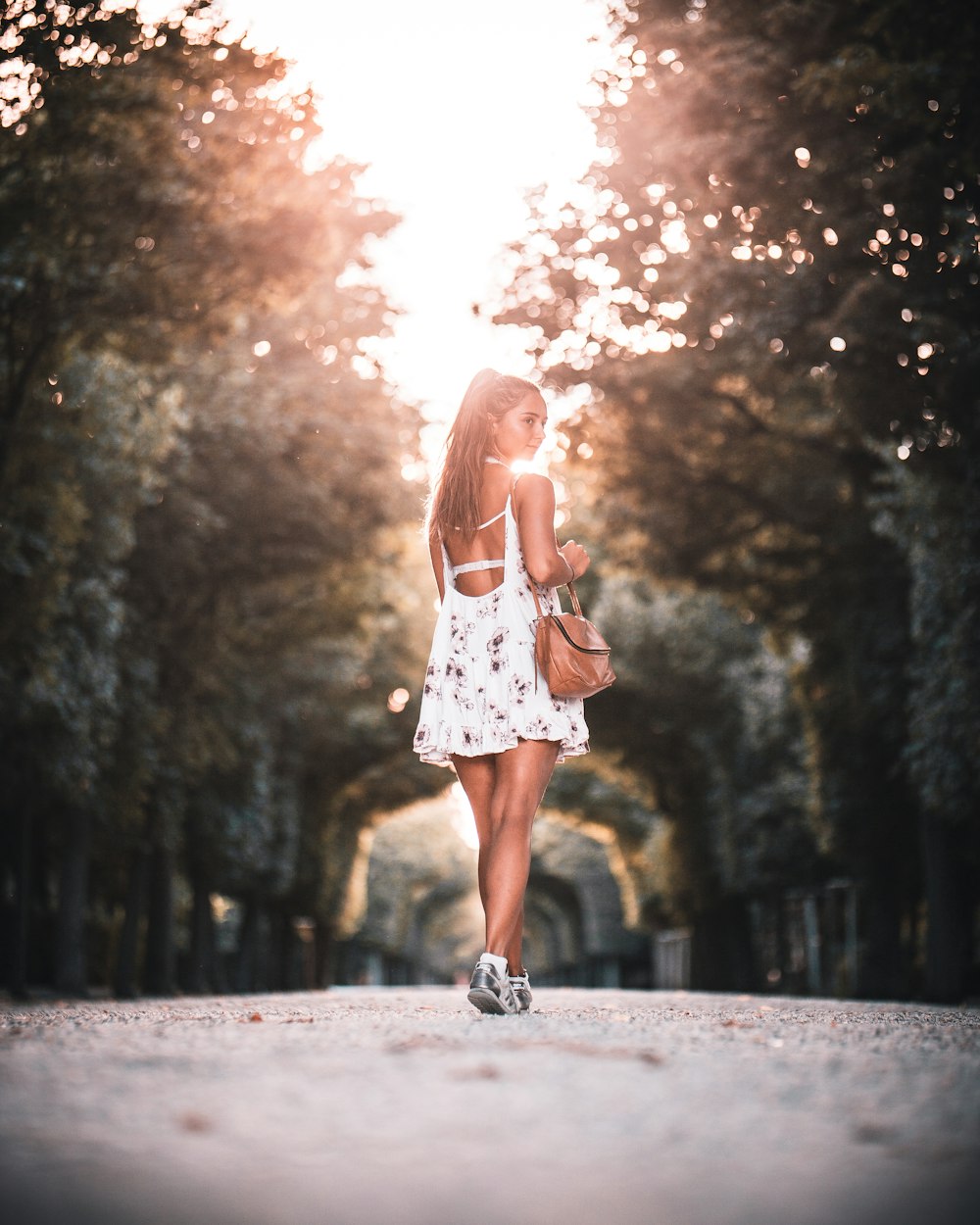 woman in white and red floral dress standing on road during daytime