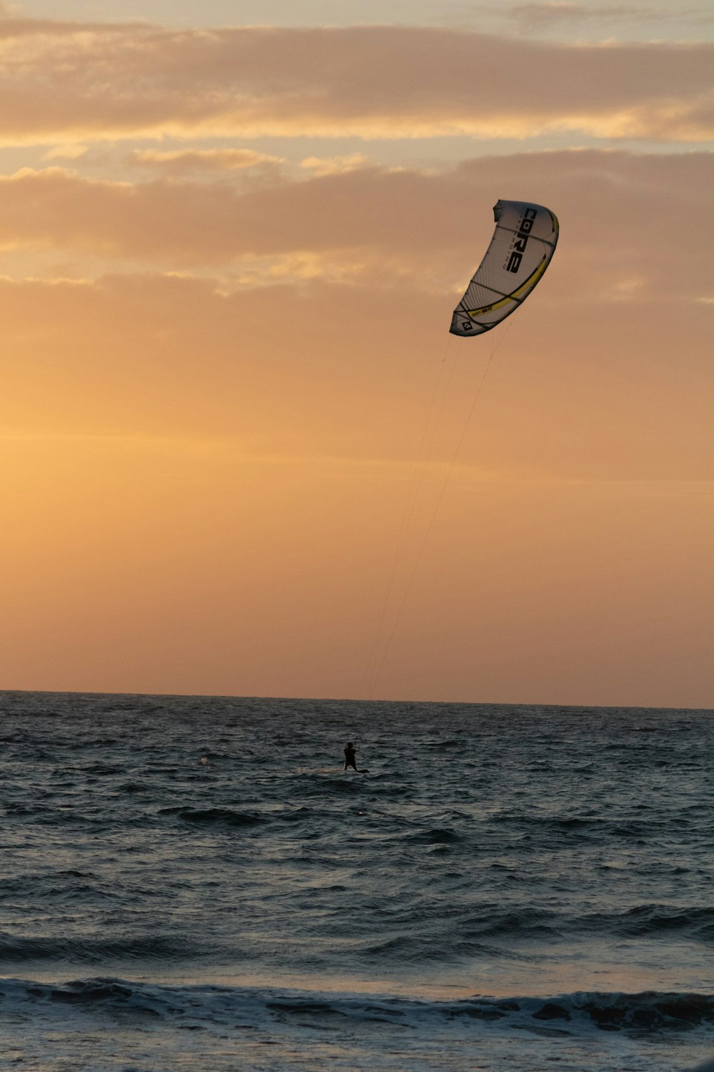 white and black kite surfing on sea during sunset