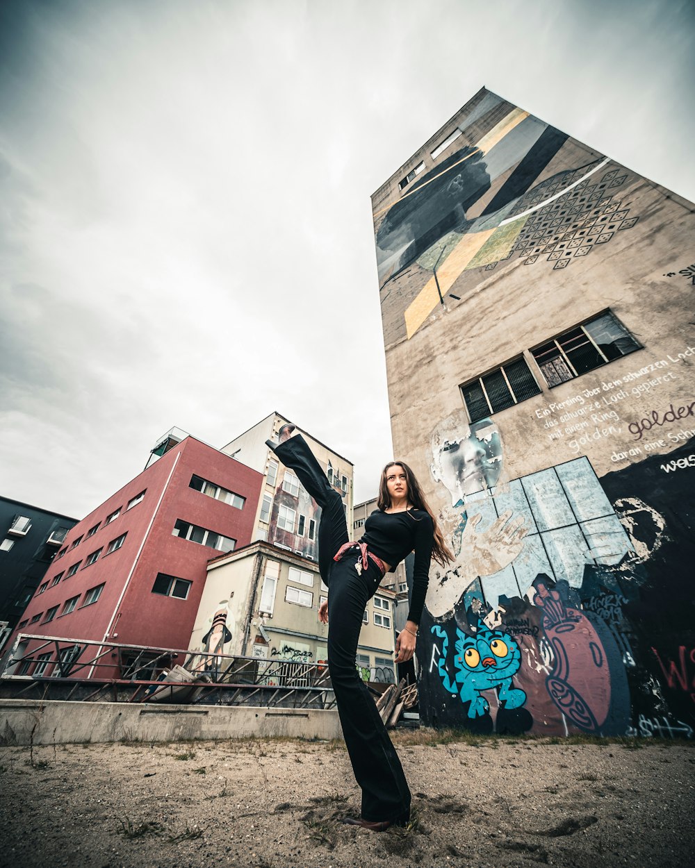 man in black t-shirt and black pants standing near graffiti wall during daytime