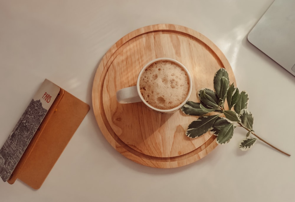 Tazza in ceramica bianca su piatto rotondo in legno marrone