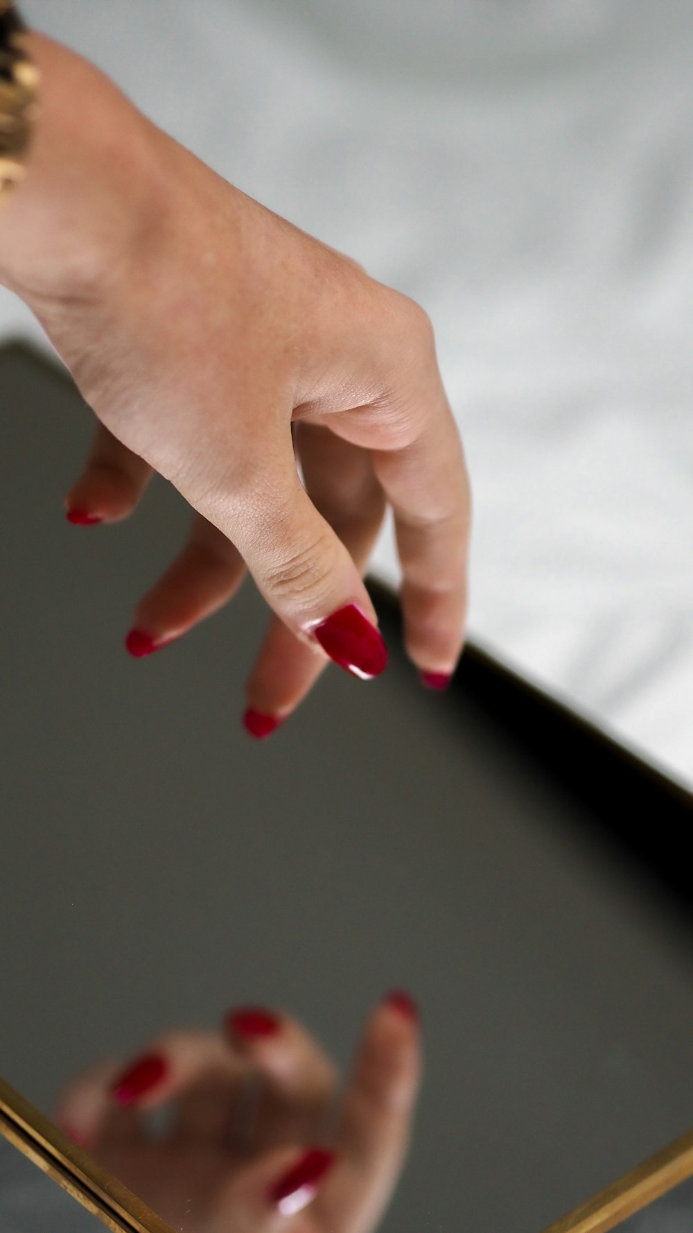 person with red manicure on white textile