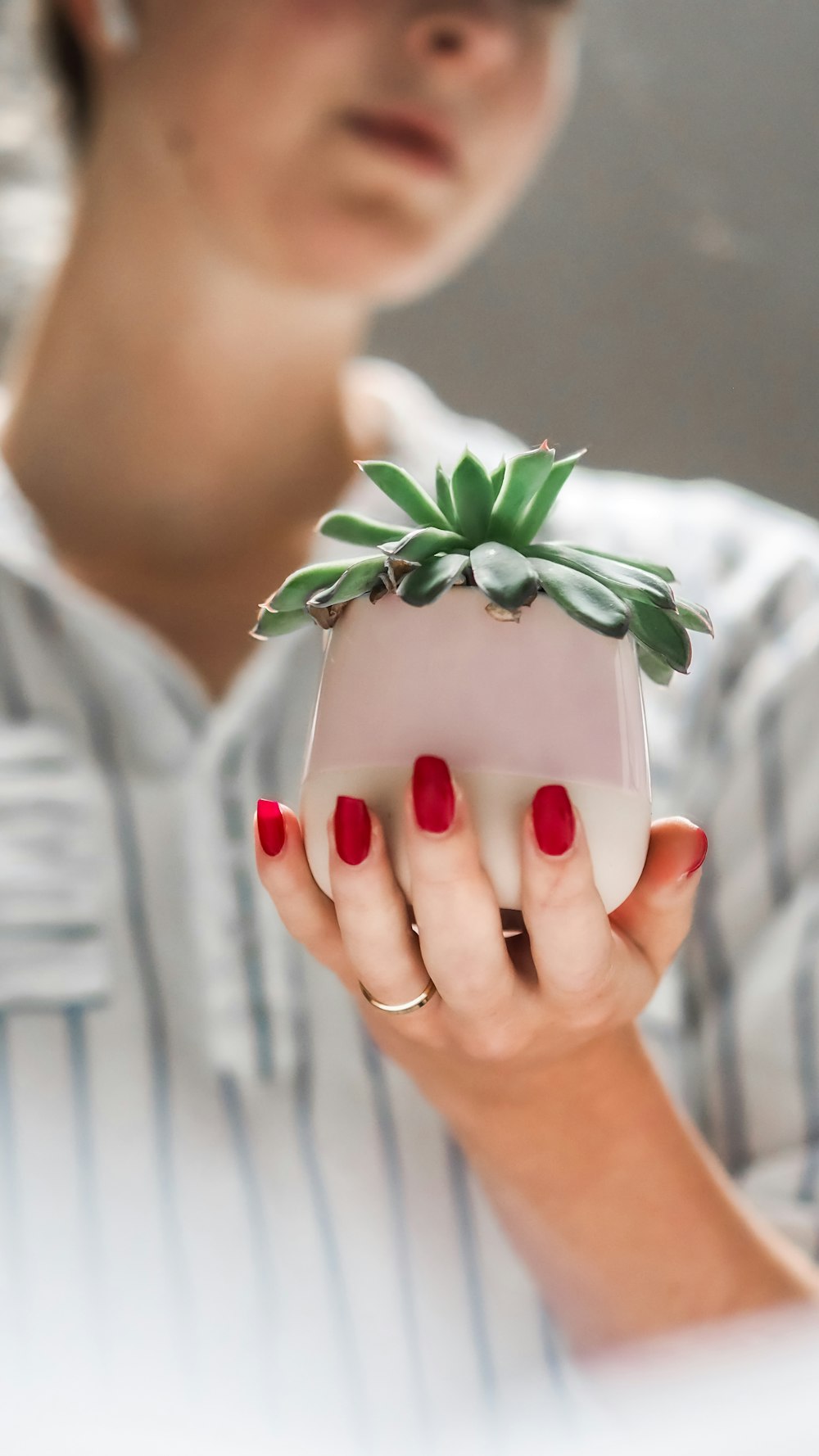 person holding white and green floral ceramic mug with green leaves