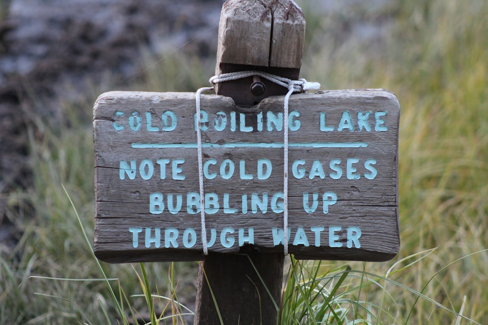a sign posted on a wooden post in the grass