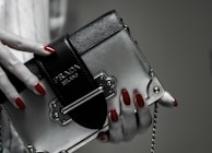 Lifestyle photo of a woman smiling while wearing elegant nail art and holding a trendy bag.