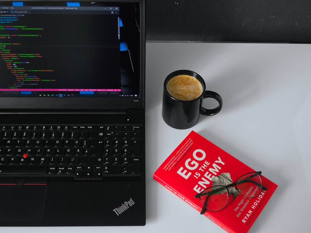 ordinateur portable noir à côté de la tasse en céramique noire