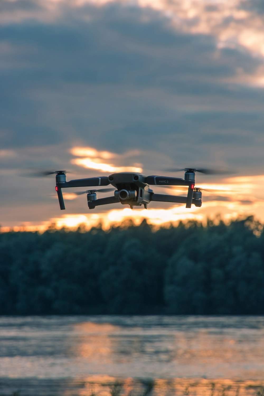 drone nero che vola sopra gli alberi verdi durante il giorno