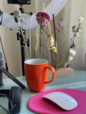 A bright, modern workspace with orange accents showing a laptop, shopping packages, and a cup of tea.