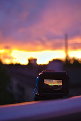 A close-up of a camera capturing a vibrant sunset.