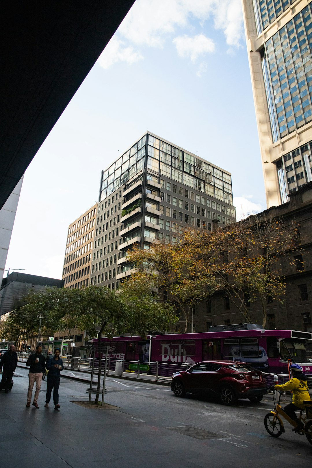 cars parked on side of the road near high rise buildings during daytime