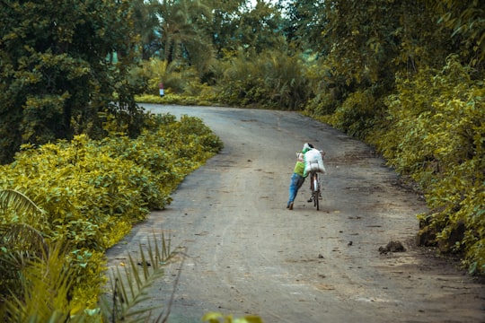person in white jacket and blue denim jeans walking on dirt road during daytime in Katni India