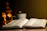 A warm, softly lit scene of an open Bible beside a glowing antique lamp on a rustic wooden table.