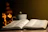 A warm, softly lit scene of an open Bible beside a glowing antique lamp on a rustic wooden table.