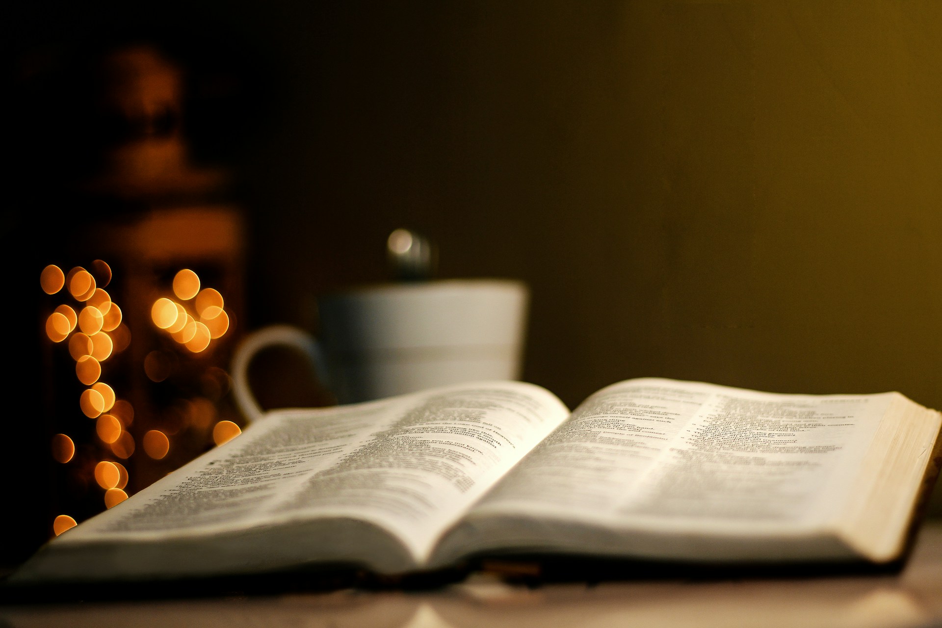 A warm, inviting shot of an open Bible with soft candlelight flickering nearby, setting a peaceful atmosphere for reflection.