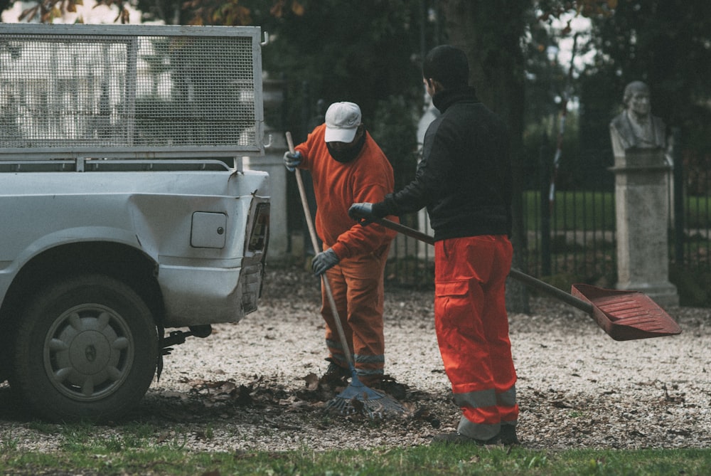 man in black long sleeve shirt and orange pants holding red and white stick