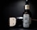 A bottle of beard oil with a silver dropper cap is displayed prominently. The label features an illustration of a bearded man and branding details. Beside it, a metallic clipper head is partially visible against a dark background.