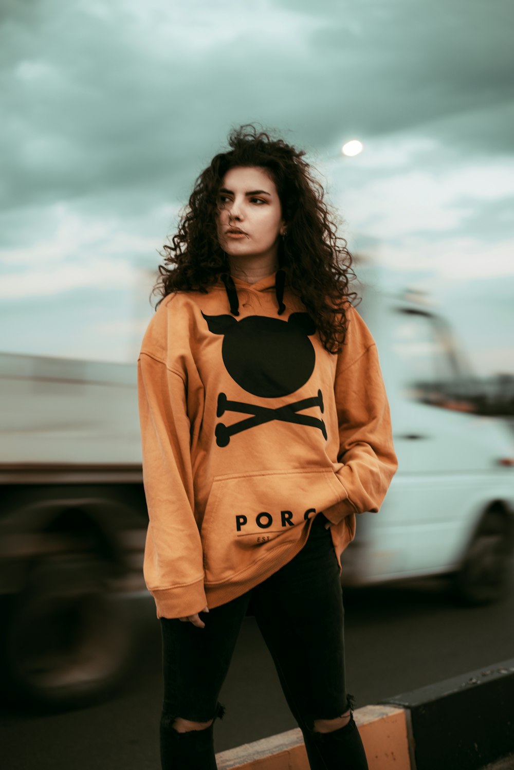 woman in orange and black adidas hoodie standing near cars during daytime