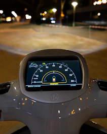 Close-up of scooter dashboard displaying speed and battery life in bright blue lighting
