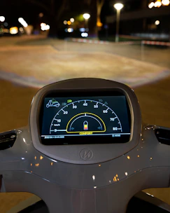 Close-up of an evox scooter’s dashboard glowing with electric-blue highlights against a dark background.