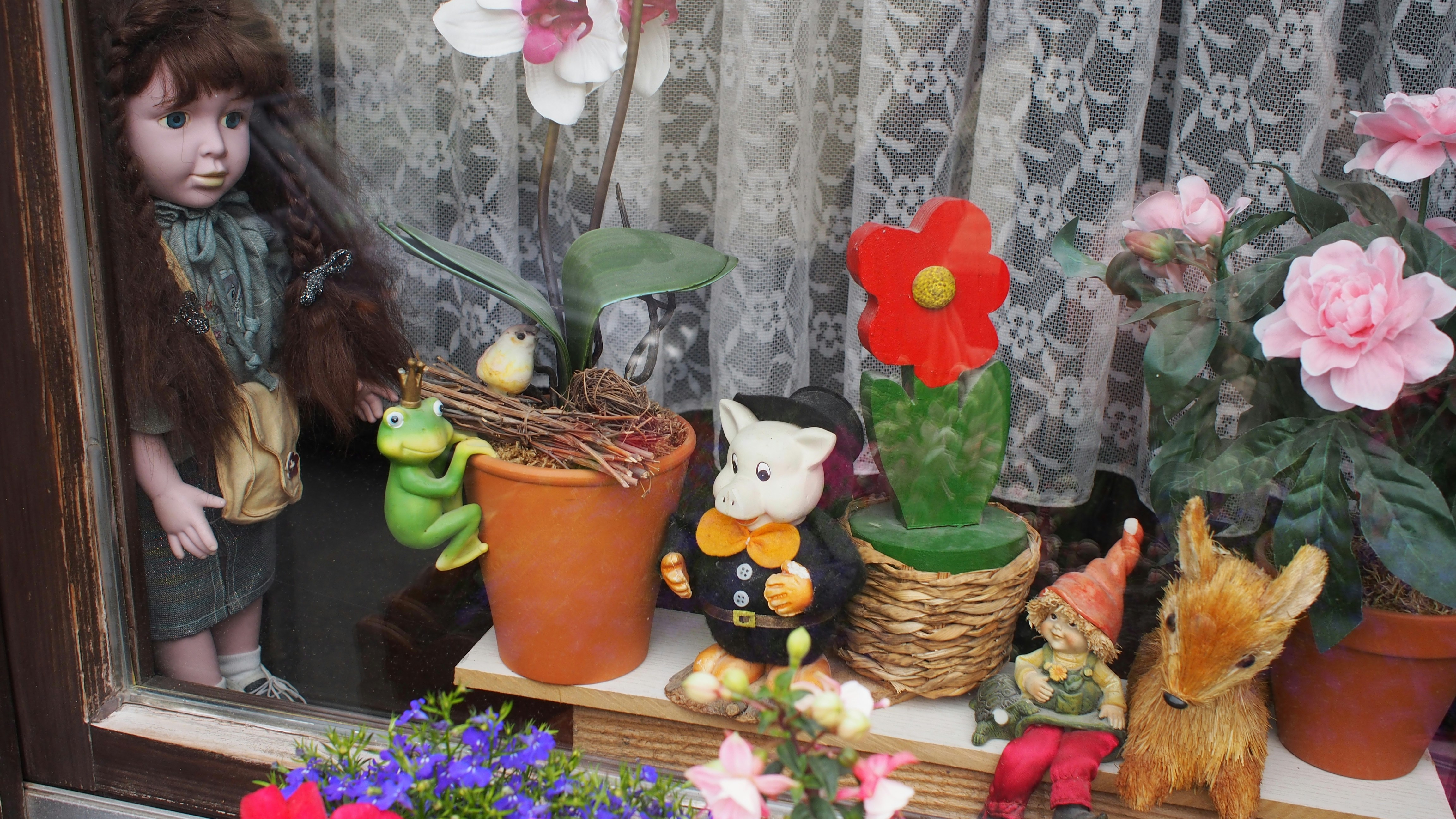 white and black cat figurine beside orange flower pot