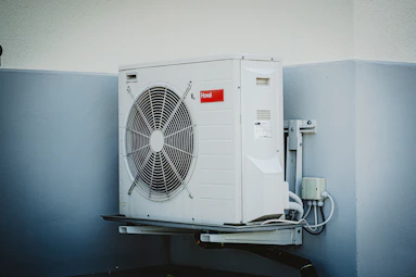 Skilled technician performing routine maintenance on a window AC unit in a residential home.