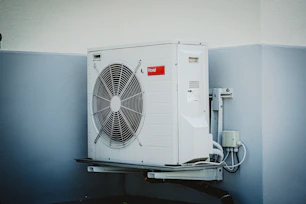 Outdoor central AC unit with visible cooling fins and pipes.