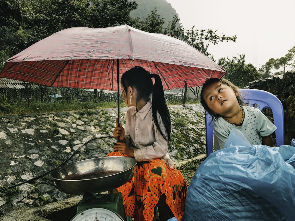 woman in white shirt holding umbrella beside woman in red dress