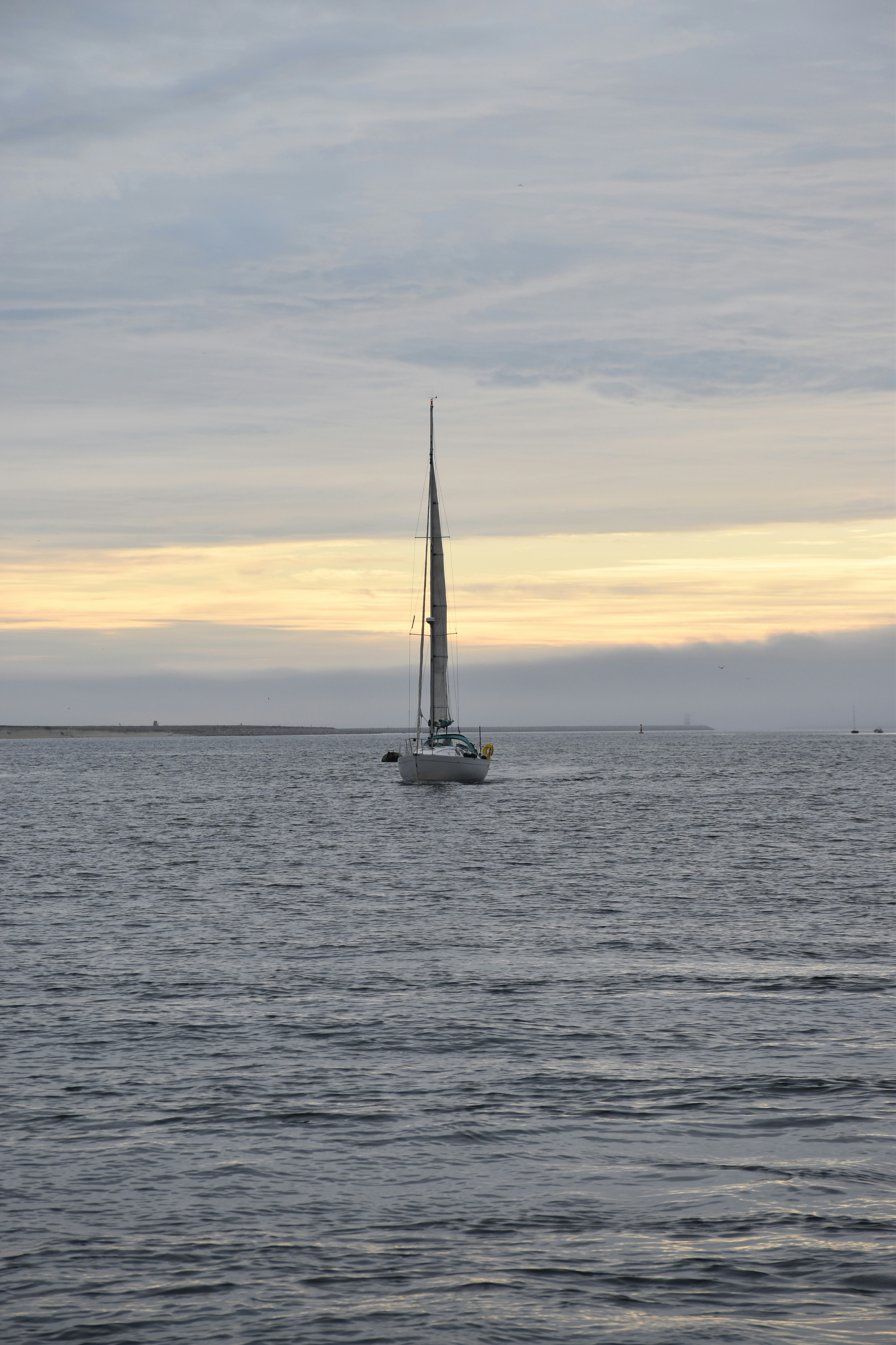 white sail boat on sea during sunset