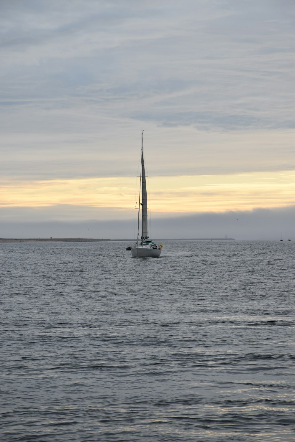 white sail boat on sea during sunset