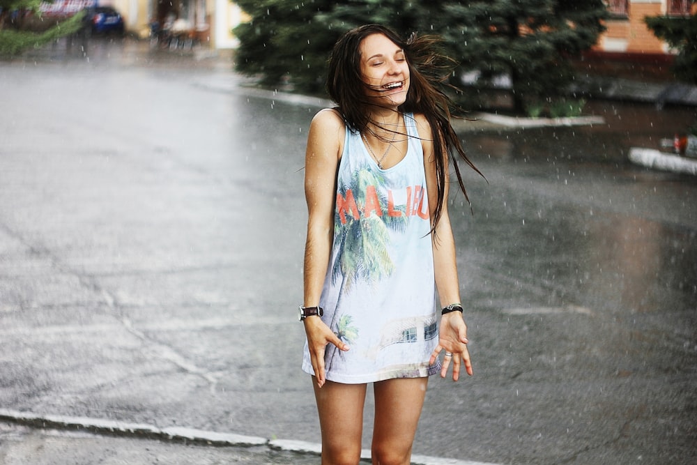 woman in white tank top and blue denim shorts standing on road during daytime