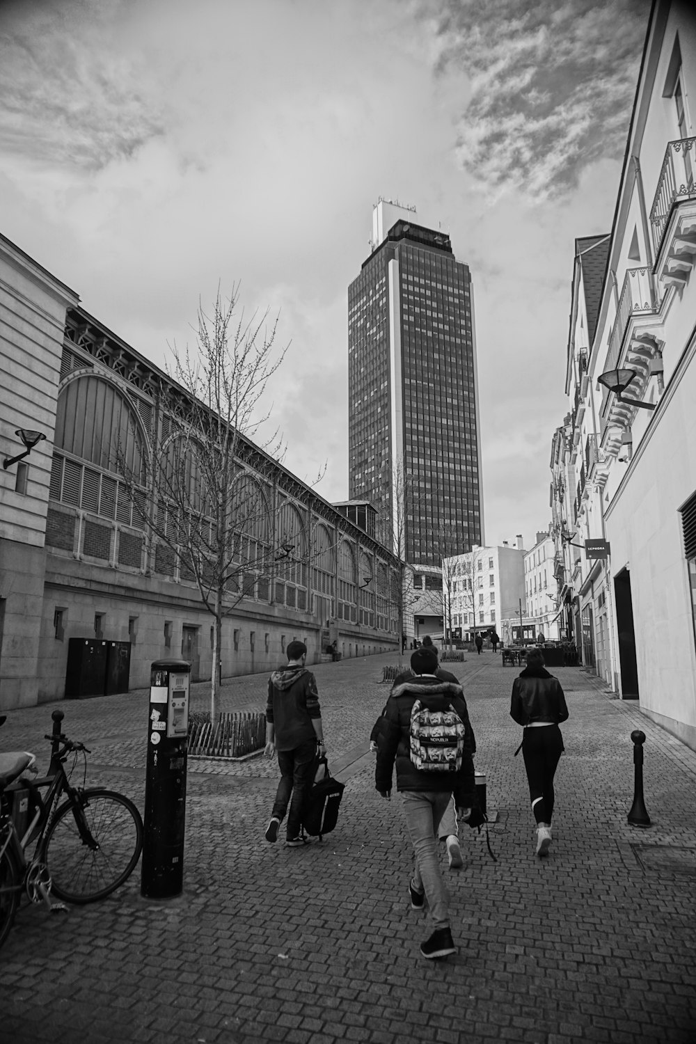 grayscale photo of man and woman walking on street