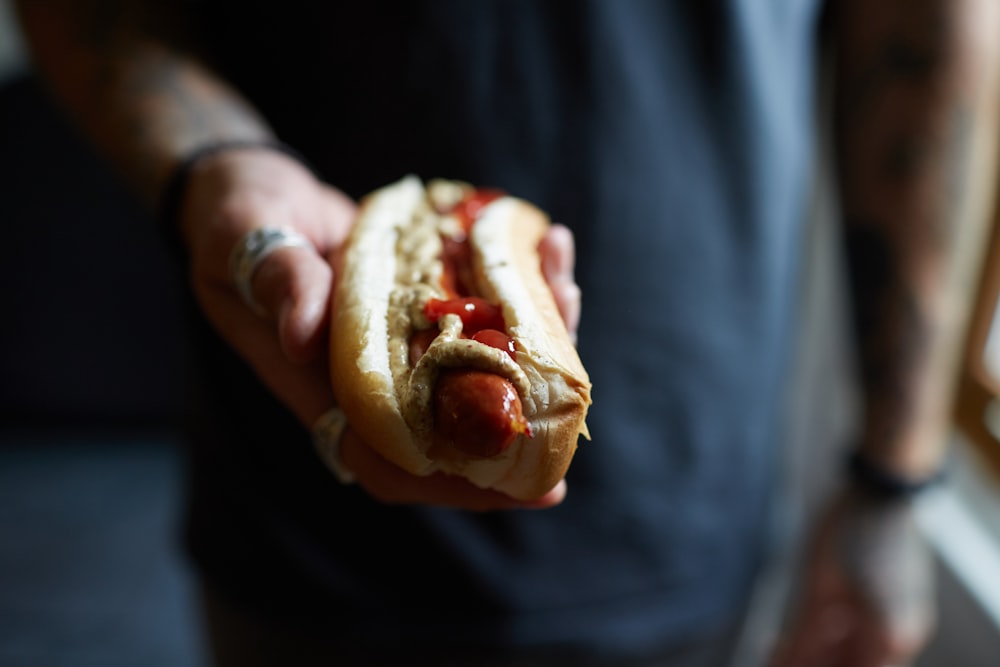 person holding hotdog sandwich with cheese