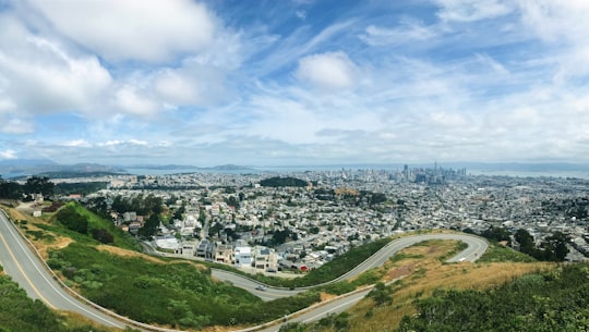 aerial view of city buildings and green grass field under blue and white sunny cloudy sky in Twin Peaks United States