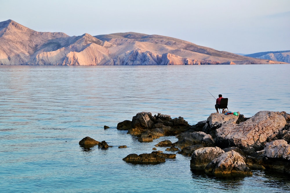 person standing on rock near body of water during daytime