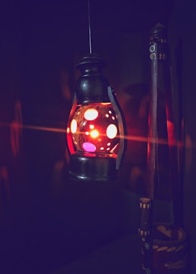 Bright red vintage camping lantern hanging from a tent pole, casting a soft glow.