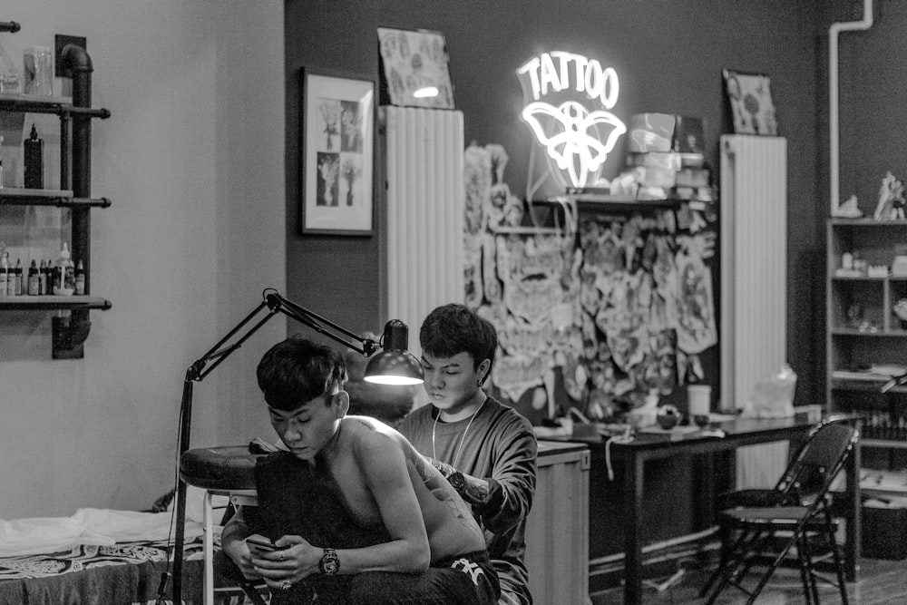 grayscale photo of 2 boys sitting on chair