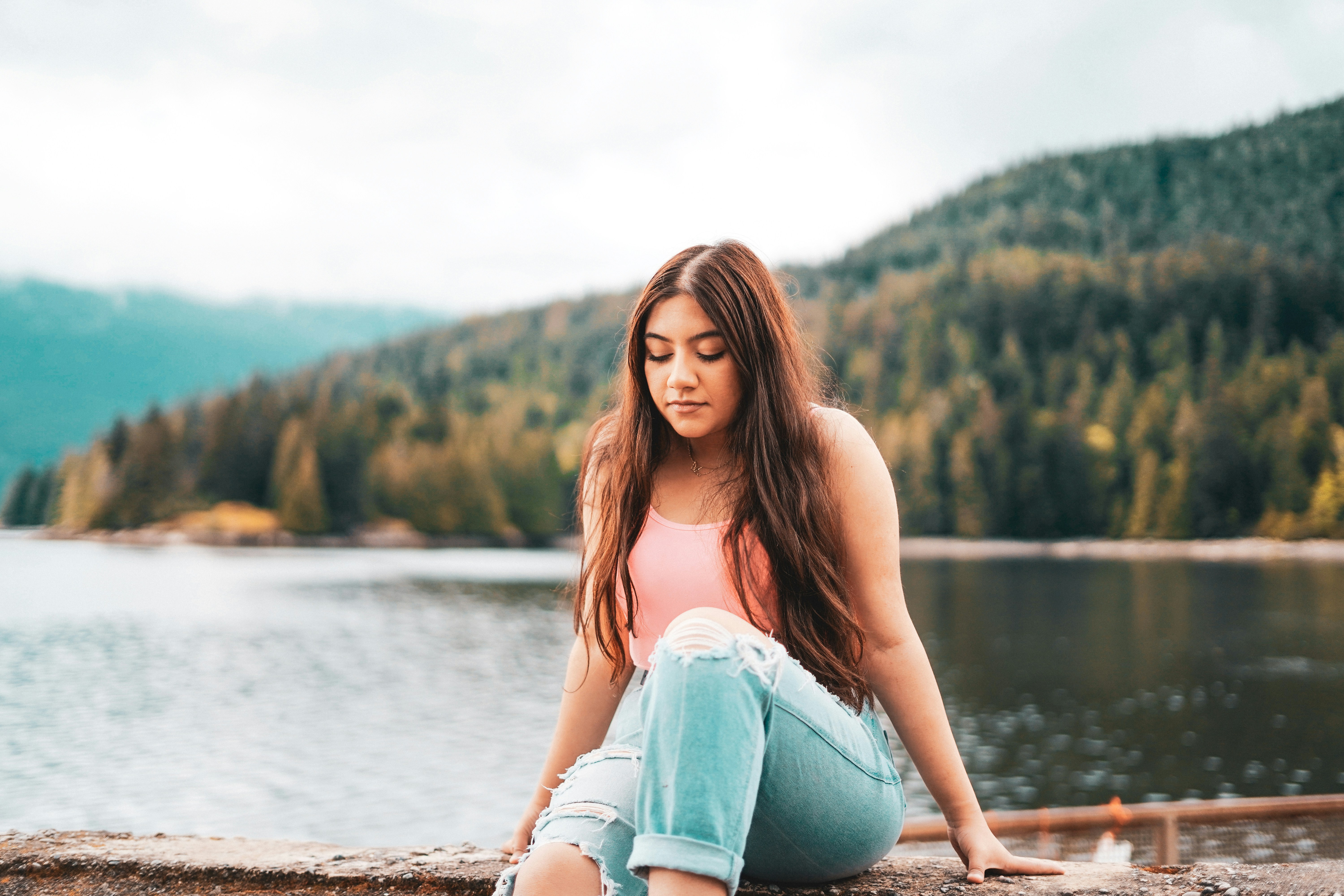 woman in blue denim jeans sitting on brown wooden dock during daytime