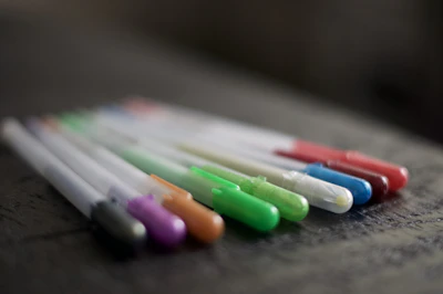 Close-up of elegant pens and markers arranged on a clean white background with subtle purple and pink accents.