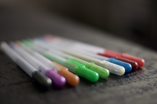 Close-up of vibrant pens and markers fanned out on a clean white surface.