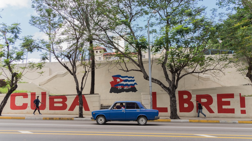 red sedan on road near trees during daytime