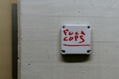 A white wall-mounted device displays a message written in red lettering, expressing a strong sentiment against law enforcement.
