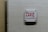 A white wall-mounted device displays a message written in red lettering, expressing a strong sentiment against law enforcement.