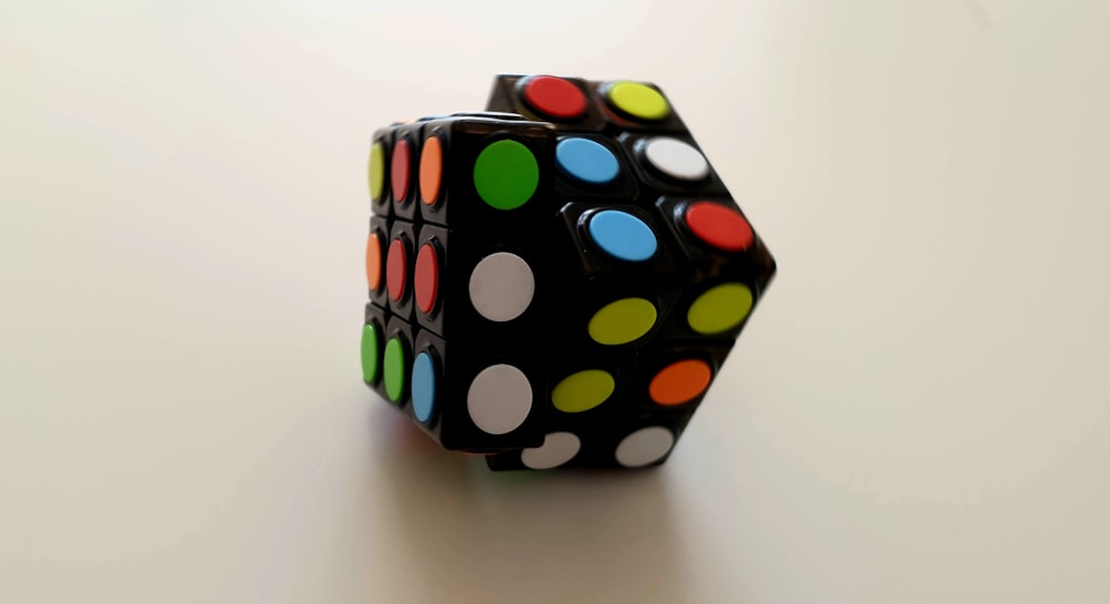 a black dice with multicolored dots on it