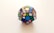 A multicolored dodecahedron puzzle featuring various geometric shapes on each face. The puzzle is displayed against a plain, light-colored background, emphasizing its vibrant colors.
